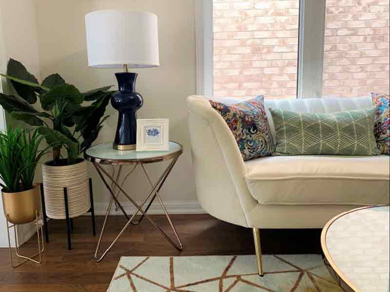 Comfortable beige sofa with side table and lamp
